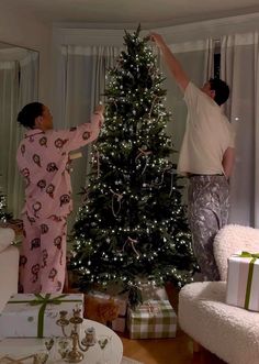 two men decorating a christmas tree in their living room