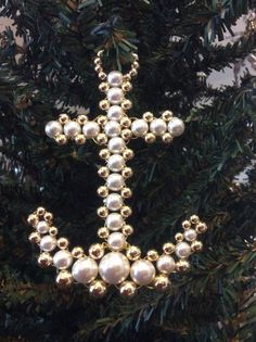 a cross ornament is hanging on a christmas tree with gold balls around it