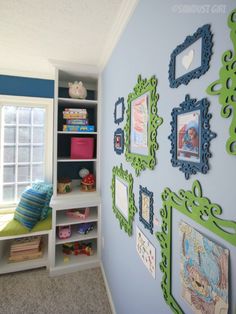 a blue and green room with pictures on the wall, bookshelves and toys