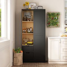 a kitchen with white cabinets and wood flooring next to an open window, filled with plants