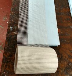 a roll of white wire mesh sitting on top of a wooden table next to a blue piece of cloth