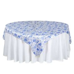 a blue and white table cloth on top of a round table with floral design in the center