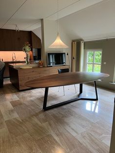 a large wooden table sitting in the middle of a living room next to a kitchen