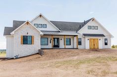 a large white house sitting in the middle of a dirt field with lots of windows