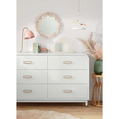 a white dresser sitting next to a mirror on top of a wooden floor