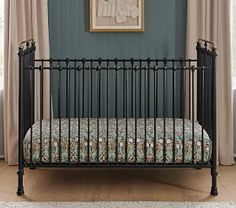 a baby crib in front of a window with curtains