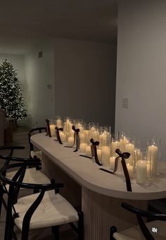 a long table topped with lots of lit candles next to a christmas tree in a room