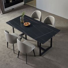 a black table with four white chairs around it and a plate of food on the table