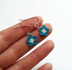 a pair of earrings with blue crocheted flowers