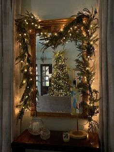 a christmas tree in the corner of a room with lights on it and a mirror