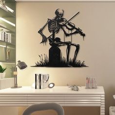 a skeleton sitting on top of a table next to a book shelf with a knife in it