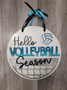 a sign that says hello volleyball season hanging on a wooden wall with a blue ribbon