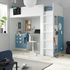 a room with a bunk bed, desk and chair next to a blue couch in front of a window