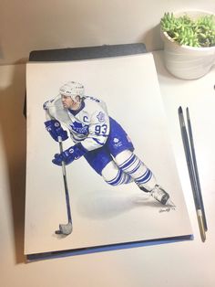 a drawing of an ice hockey player is shown on the table next to a potted plant