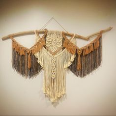 a piece of art made out of wood and fringes hanging from a wooden pole