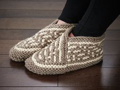 a woman's feet wearing slippers on top of a wooden floor