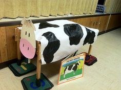 a cow statue sitting on top of a wooden floor next to two children's toys