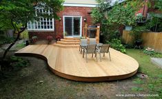 a wooden deck with chairs and table in the backyard