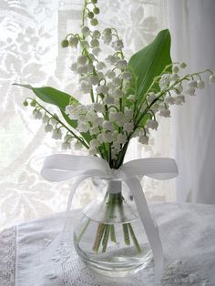 a vase filled with white flowers sitting on top of a table next to a window