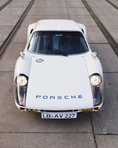 an old porsche car is parked on the side of the road in front of some tracks