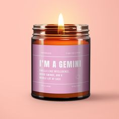 a candle that is sitting on top of a pink surface with the words i'm a gemini in it