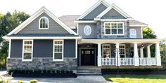 a gray house with white trim on the front porch and two story entryway leading up to it