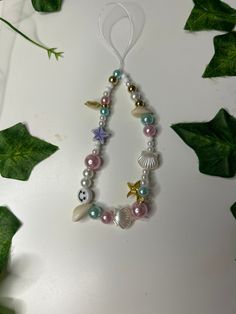 a necklace with shells and pearls hanging from it's side on a white surface