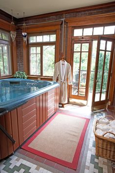 a large jacuzzi tub in the middle of a room with wooden doors and windows