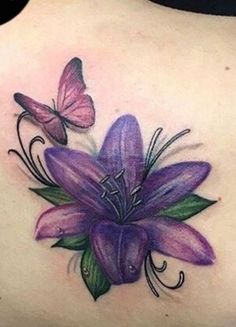 a woman's back tattoo with purple flowers and butterflies on the top of it