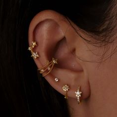 a woman's ear is adorned with gold stars and cubics, which are attached to the side of her ear