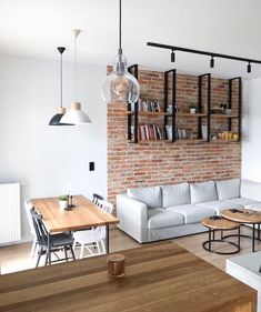 a living room filled with furniture and a brick wall mounted book shelf above the couch