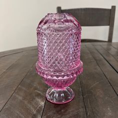 a pink glass candle holder sitting on top of a wooden table