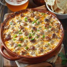 a casserole dish with meat and cheese in it on a cutting board next to some chips