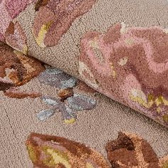 a close up of a rug on the floor with flowers and leaves in pink, brown, yellow and blue colors