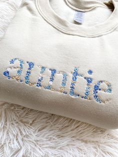 an embroidered sweatshirt with the word spring on it sitting on top of a fluffy white blanket