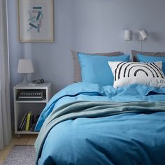 a bed with blue sheets and pillows in a bedroom