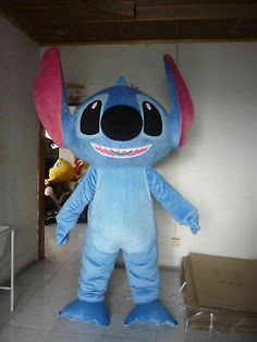 an inflatable blue and pink costume standing next to a wall