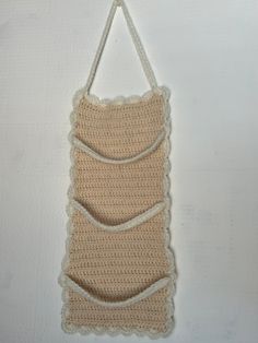 a crocheted bag hanging on a wall with string attached to the back of it