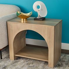 a small wooden table with a vase on top and a lamp on the end shelf