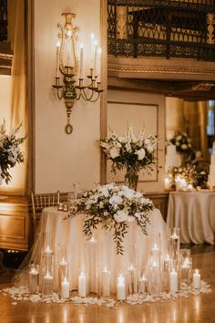 a table with candles and flowers on it in the middle of a room filled with tables