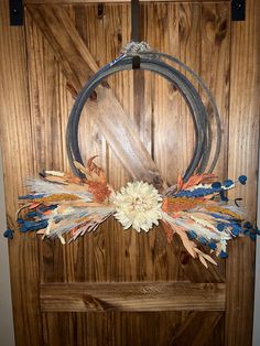 a wooden door with a metal circle and flowers on the front, hanging from it's side