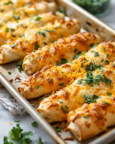 two trays filled with chicken covered in cheese and parsley