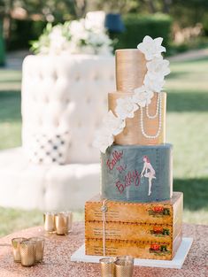 a three tiered cake sitting on top of a table next to gold cup holders