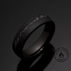 a black wedding ring with white writing on it