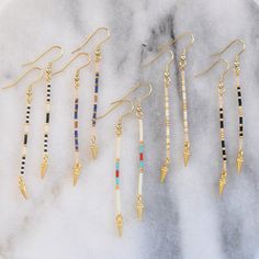 Edgy minimalism at its finest. These simple, long beaded stick earrings in a lean linear shape are just the right thing when you want a subtly cool accent. A tiny gold spike finishes the look with don't-mess-with-me edge. beaded gold-plated pin with tiny glass seed beads gold-plated stainless steel earwire hooks lead-free and nickel-free gold-plated spike charm plastic earring back 3 inches long packaged on a logo kraft card in a clear resealing bag Simple Bead Earrings, Long Beaded Earrings, Pebble Jewelry, Diy Earrings Easy, Homemade Bracelets, Stick Earrings, Beaded Earrings Diy, Plastic Earrings, Handmade Jewelry Diy