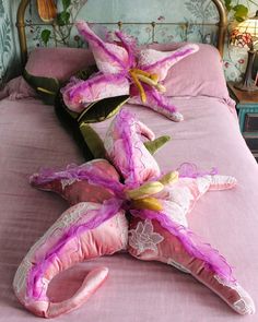 two pillows are laying on the bed with pink sheets and decorative decorations in front of them