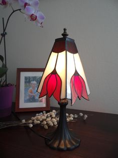 a lamp that is sitting on top of a table next to some rocks and flowers