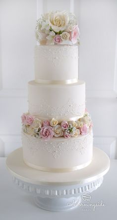 a three tiered white wedding cake with pink and white flowers