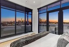 a bedroom with large windows overlooking the city