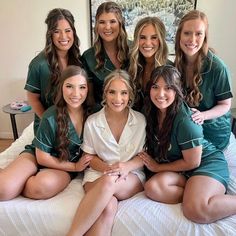 a group of beautiful women sitting on top of a bed next to eachother